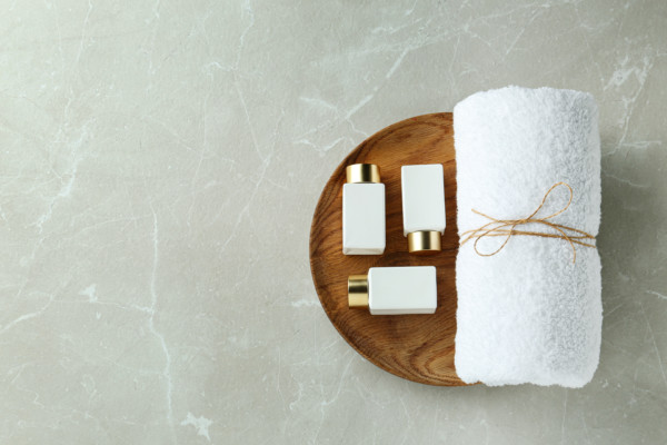 Three mall soap bottles on a wooden plate with a towel tied up